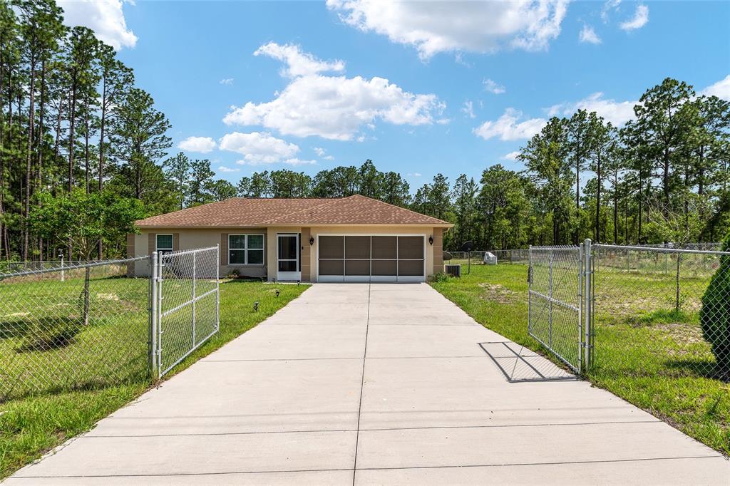 A single-story house with a concrete driveway and a chain-link fence in the front yard — 13130 SW 76TH LANE, DUNNELLON, FL