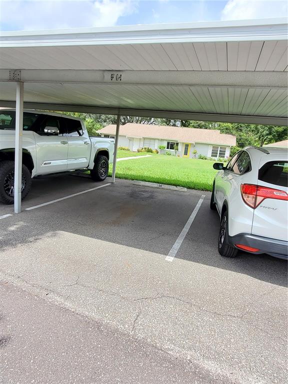 A covered parking carport with two vehicles parked in designated spaces — 1907 CANTERBURY LANE UNIT 14, SUN CITY CENTER, FL