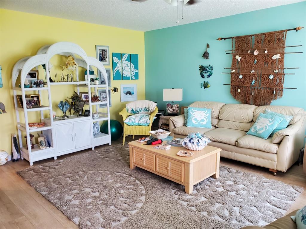 A living room features a beige sofa, a wooden coffee table, and a white shelving unit — 1907 CANTERBURY LANE UNIT 14, SUN CITY CENTER, FL