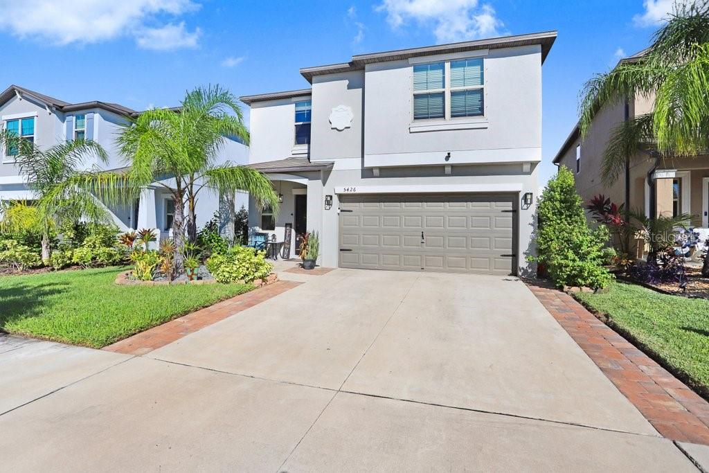 A two-story suburban house features a concrete driveway, a two-car garage, and a landscaped yard — 5426 RAINWOOD MEADOWS DRIVE, APOLLO BEACH, FL