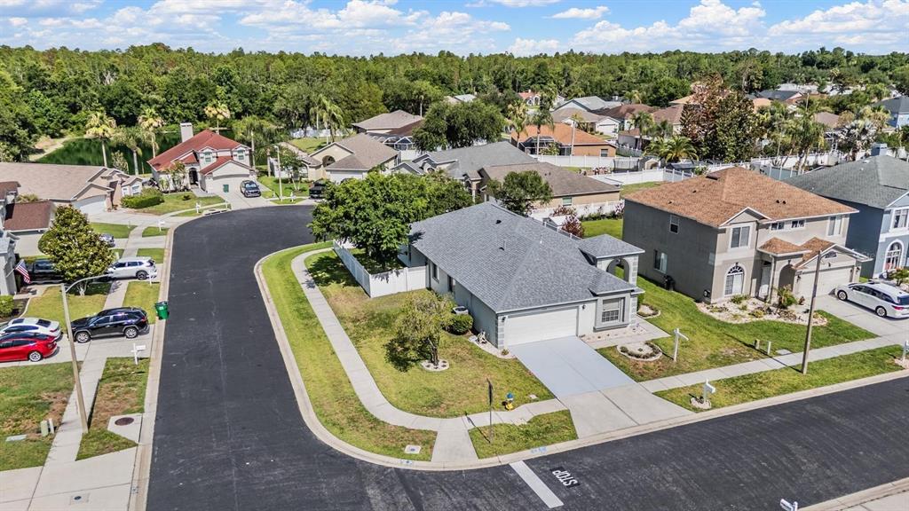An aerial view shows a suburban neighborhood with houses, paved streets, and a stop sign — 4940 WOODMERE ROAD, LAND O LAKES, FL