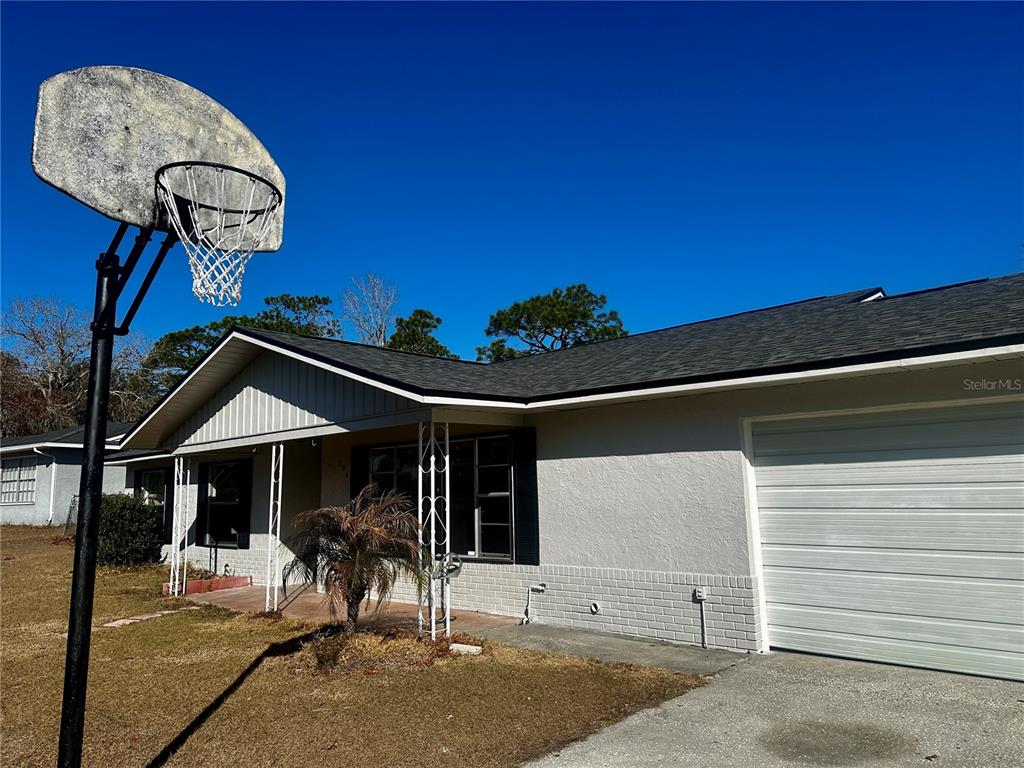 A single-story house with a white brick facade, a garage, and a basketball hoop outside — 606 WATER ROAD, OCALA, FL