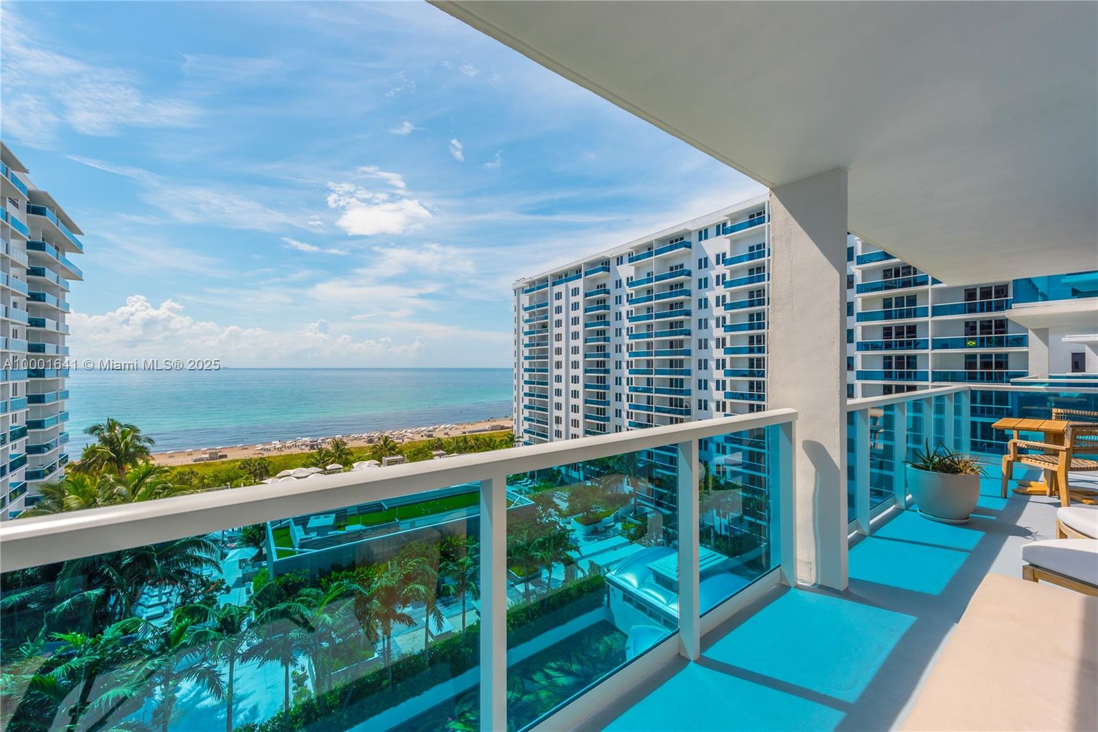 A balcony with glass railings overlooks a beach, ocean, and neighboring high-rise buildings — 102 24 ST # 1040, Miami Beach FL 33139, MIAMI BEACH, FL