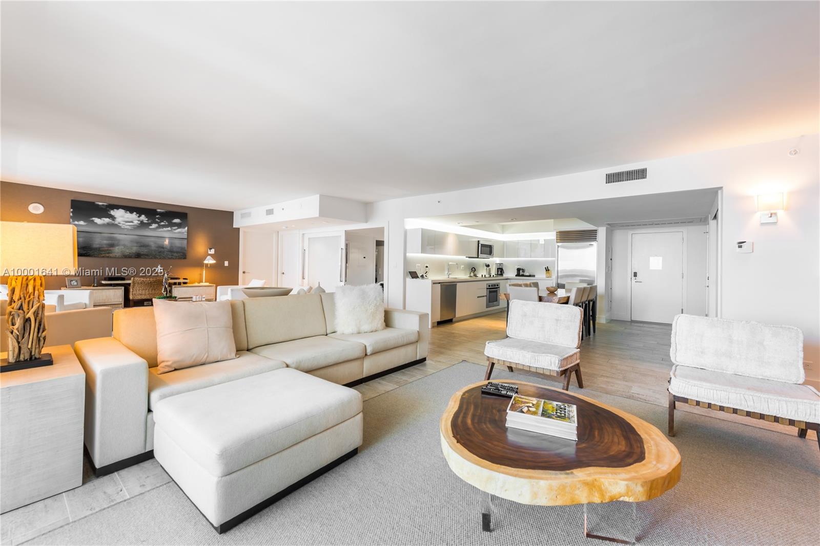 A living room with a sectional sofa, a live-edge coffee table, and an open kitchen — 102 24 ST # 1040, Miami Beach FL 33139, MIAMI BEACH, FL