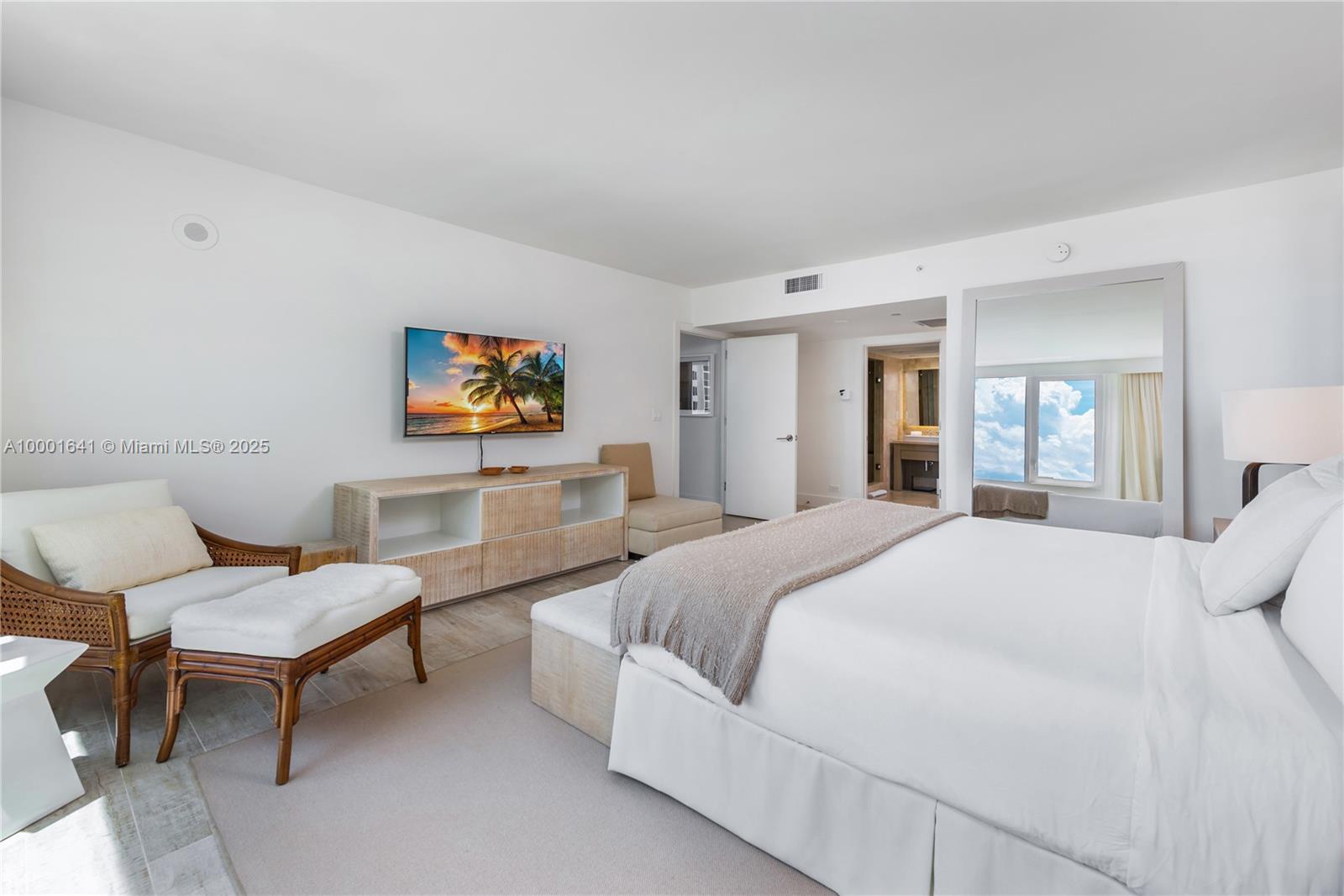 A bedroom features a bed, a television, a wooden console, and a seating area — 102 24 ST # 1040, Miami Beach FL 33139, MIAMI BEACH, FL