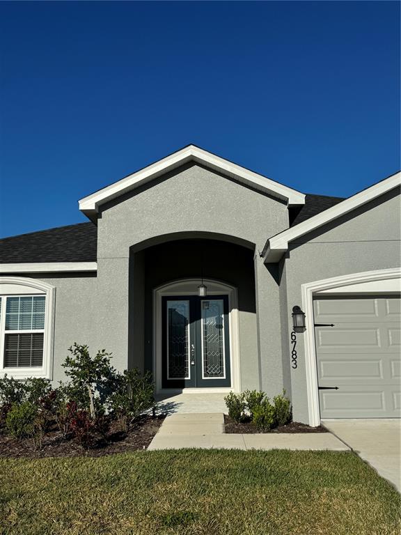 A gray stucco house exterior features a covered entryway with double glass doors — 6783 TREYMONT DRIVE, LAKELAND, FL