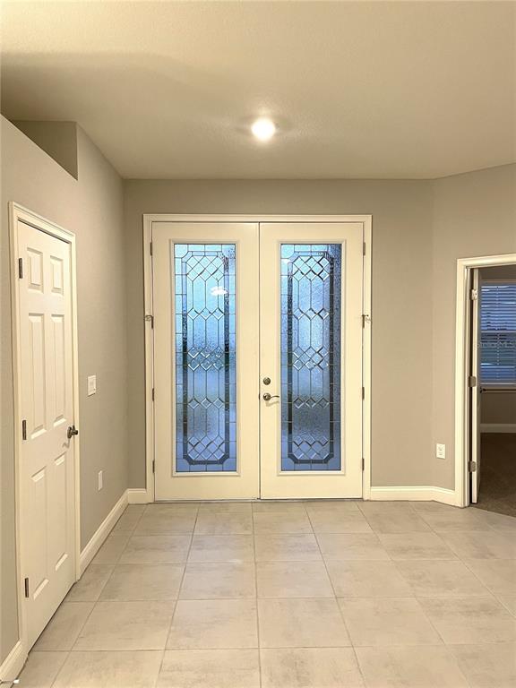 An entryway features double glass-paneled doors, light gray walls, and large square floor tiles — 6783 TREYMONT DRIVE, LAKELAND, FL