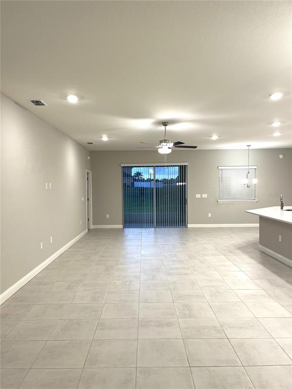 An open-concept living area features light gray tile flooring, recessed lighting, and a sliding glass door — 6783 TREYMONT DRIVE, LAKELAND, FL