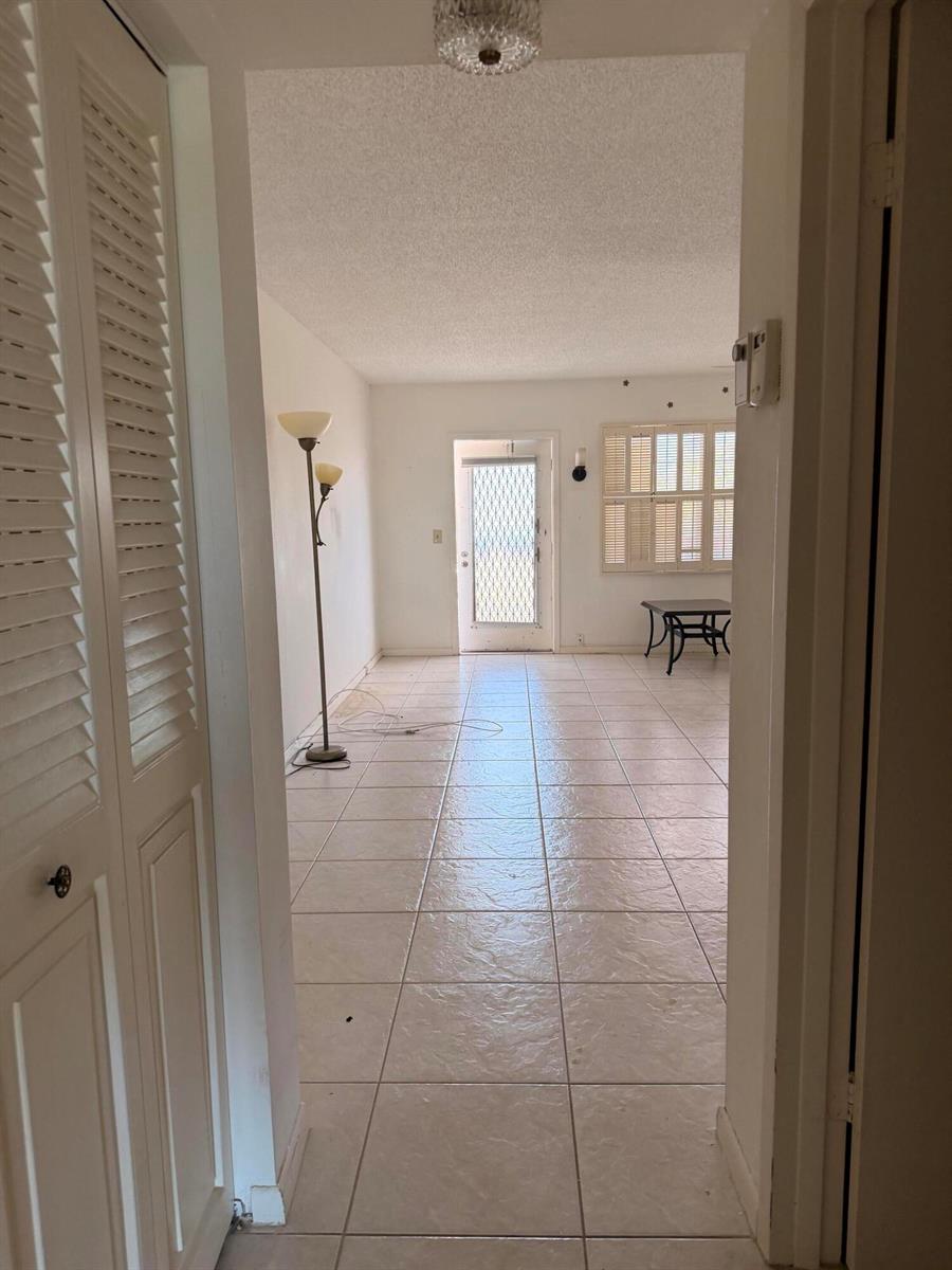 A view through a doorway into a tiled living area with a glass-paned exterior door — 4074 Cornwall D, Boca Raton FL 33434, BOCA RATON, FL