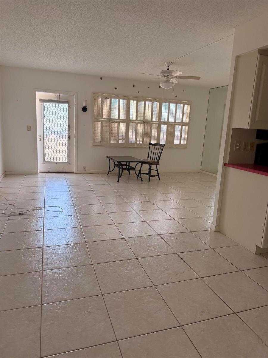 A tiled dining area features a ceiling fan, plantation shutters, and a single wooden chair — 4074 Cornwall D, Boca Raton FL 33434, BOCA RATON, FL