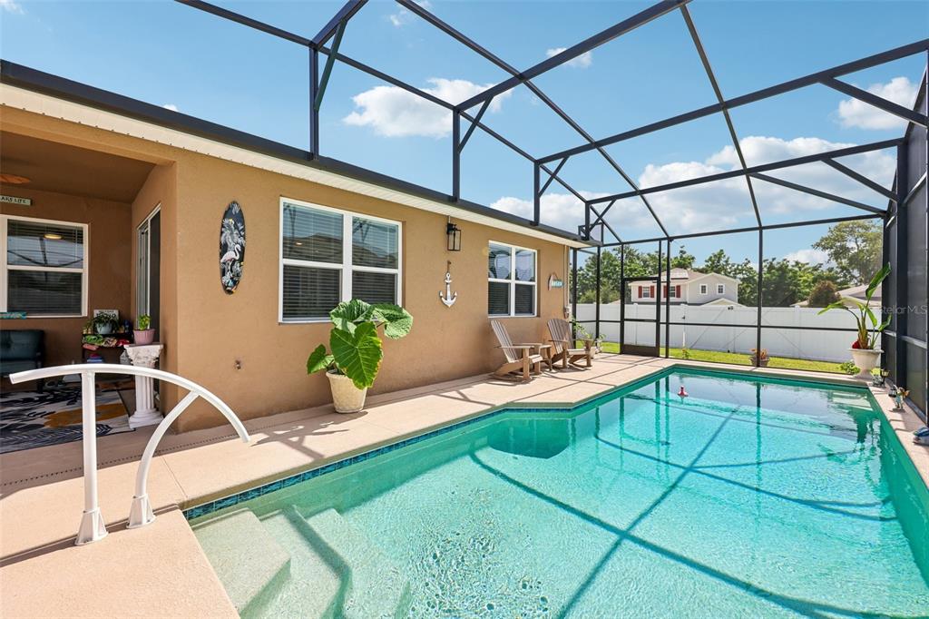 A screened-in patio features a swimming pool, lounge chairs, and a tan exterior wall — 8077 CHERRYSTONE STREET, LEESBURG, FL