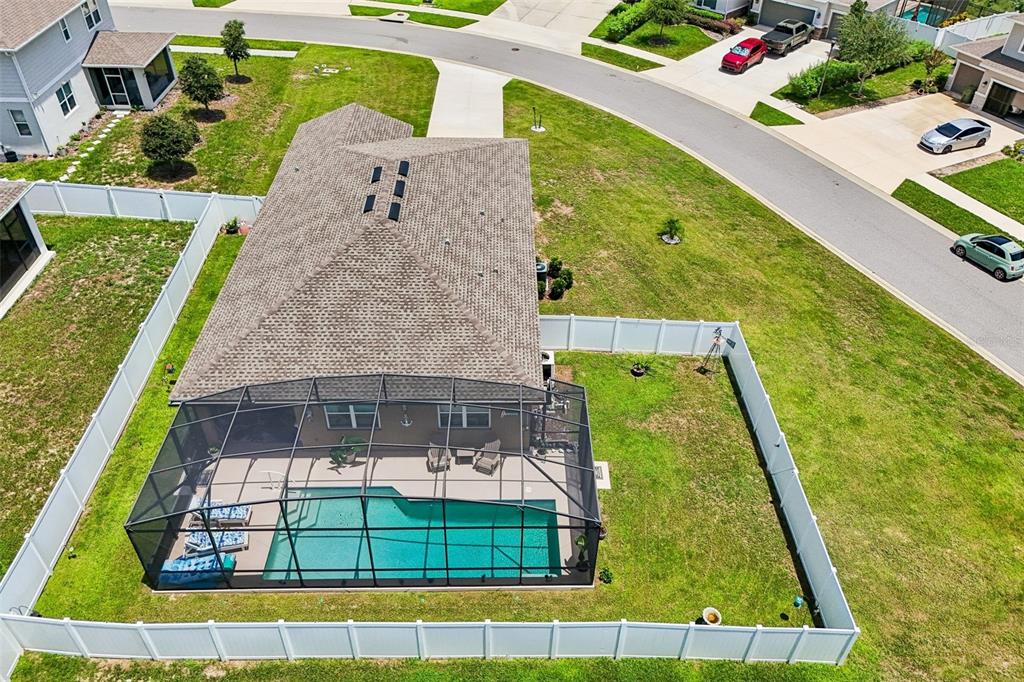 An aerial view of a house with a screened-in pool and a fenced backyard — 8077 CHERRYSTONE STREET, LEESBURG, FL