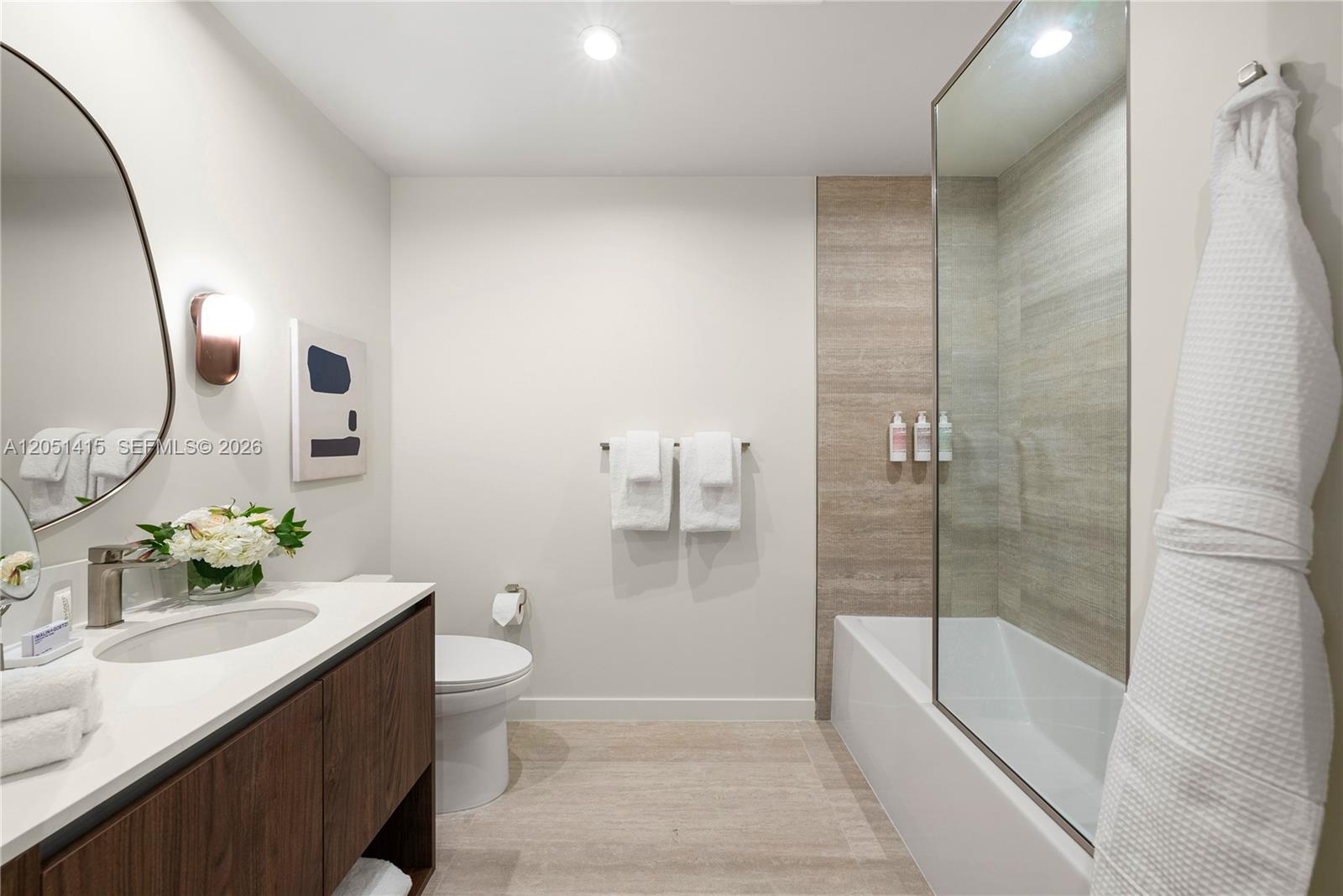 A modern bathroom features a wood vanity, white countertop, toilet, and a glass-enclosed tub shower — 1611 SW 2nd Ave # 516, Miami FL 33129, MIAMI, FL