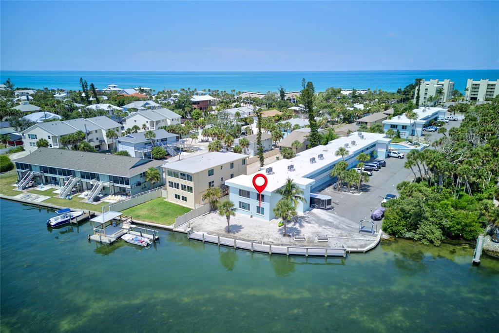 An aerial view of a waterfront apartment complex with a boat dock and parking lot — 5055 N BEACH ROAD UNIT 101, ENGLEWOOD, FL
