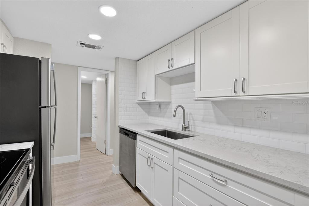 A kitchen features white shaker cabinets, light quartz countertops, a subway tile backsplash, and stainless appliances — 3795 41ST LANE S UNIT A, ST PETERSBURG, FL