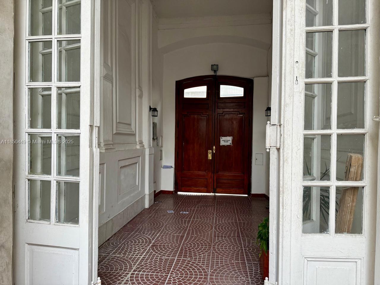 A tiled entryway features white paneled walls and a large, arched wooden double door — 945 Defensa St San Telmo, FL 945, FL