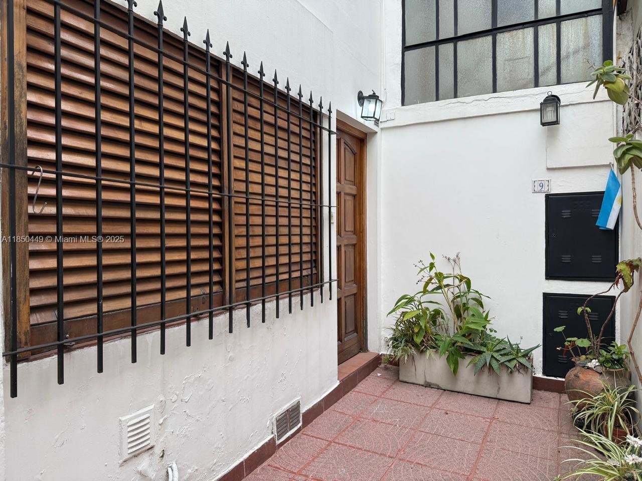 A small outdoor patio with a wooden door, shuttered window, and potted plants — 945 Defensa St San Telmo, FL 945, FL