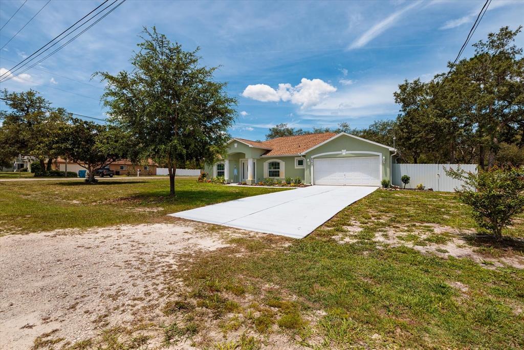 A light green single-story house with a white garage door and a concrete driveway — 8343 NITTANY ROAD, WEEKI WACHEE, FL