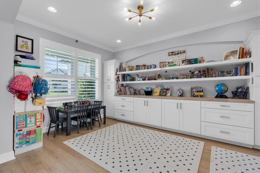 A children's playroom features built-in white cabinetry, open shelving, a small table, and a rug — 4434 TATUM LOOP, ODESSA, FL