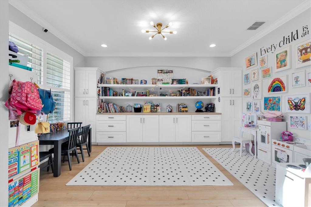 A bright playroom features built-in white cabinetry, open shelving, a desk, and a patterned rug — 4434 TATUM LOOP, ODESSA, FL