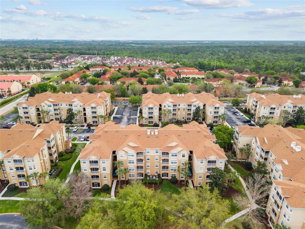 An aerial view of several multi-story apartment buildings with tan siding and brown roofs — 2774 ALMATON LOOP UNIT 105, KISSIMMEE, FL