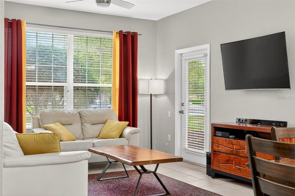 A living room features a white sofa, a wooden coffee table, and a wall-mounted television — 2774 ALMATON LOOP UNIT 105, KISSIMMEE, FL