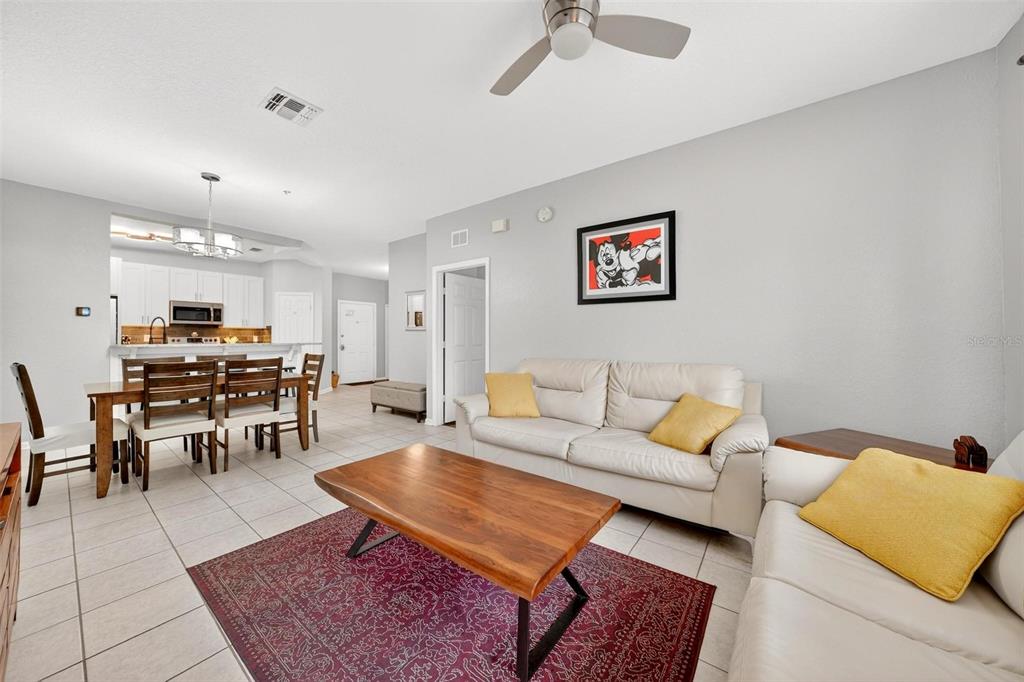 A living room with a white sofa, wooden coffee table, and an adjacent dining area — 2774 ALMATON LOOP UNIT 105, KISSIMMEE, FL