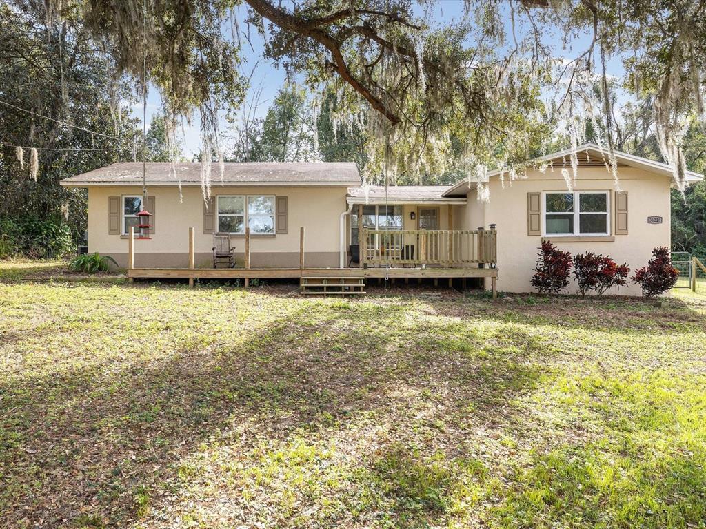 A single-story house with a wooden deck and beige siding sits on a grassy lot — 36228 CLINTON AVENUE, DADE CITY, FL