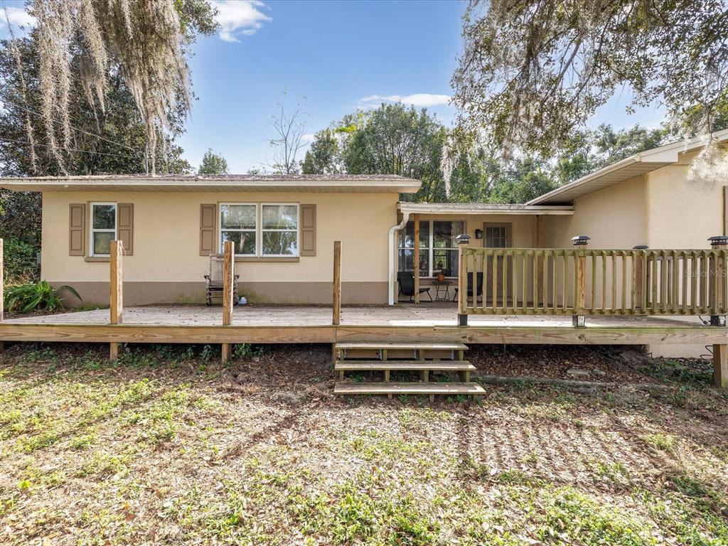 A single-story house with a large wooden deck and stairs in a wooded yard — 36228 CLINTON AVENUE, DADE CITY, FL