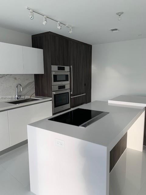 A modern kitchen features white countertops, dark wood cabinetry, and a built-in oven and microwave — 851 NE 1st Ave # 2110, Miami FL 33132, MIAMI, FL