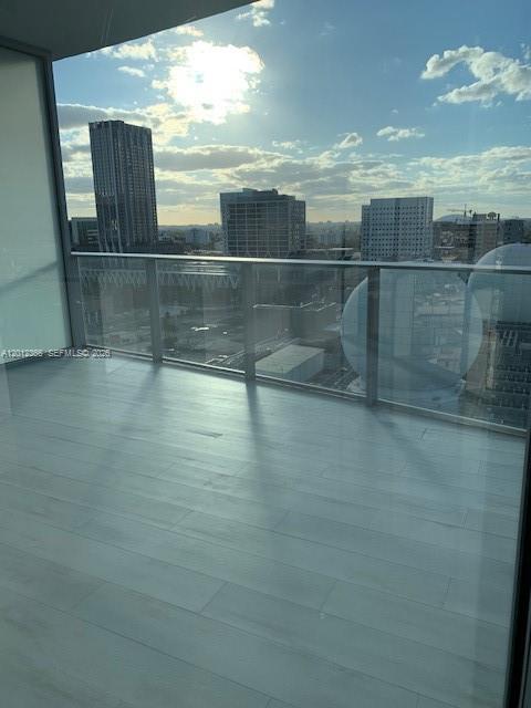 A balcony with light wood-look flooring overlooks a city skyline under a bright, sunny sky — 851 NE 1st Ave # 2110, Miami FL 33132, MIAMI, FL