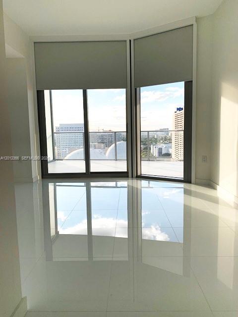 A bright room with white tile floors and large windows overlooking a city skyline — 851 NE 1st Ave # 2110, Miami FL 33132, MIAMI, FL