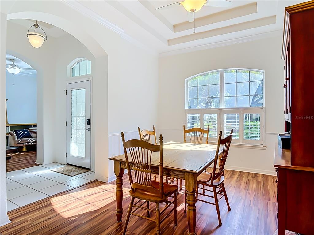 A dining room with a wooden table, chairs, hardwood floors, and a large arched window — 14 EGRET DRIVE, PALM COAST, FL