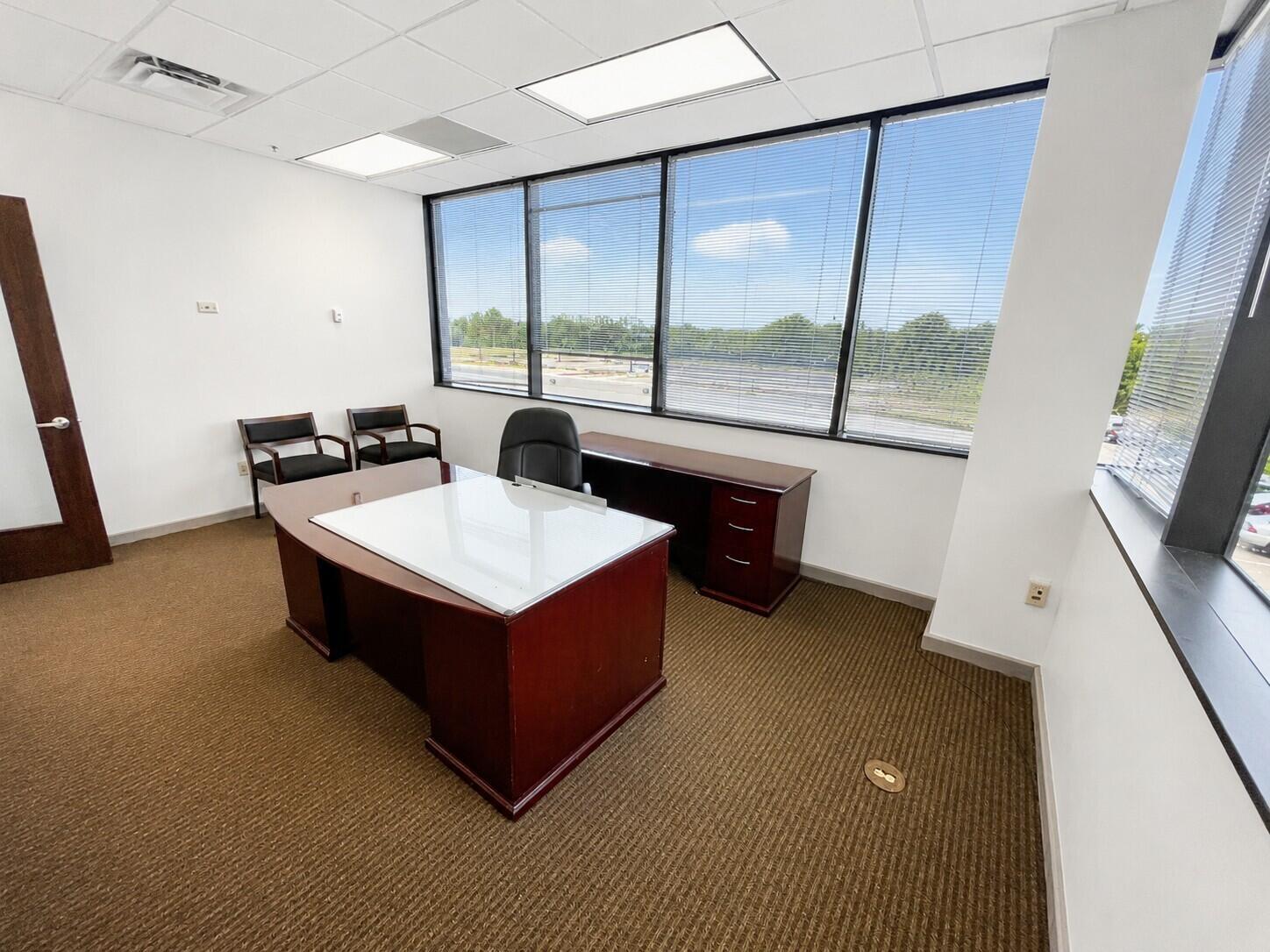 An office with a dark wood desk, two guest chairs, and large windows overlooking parking — 1200 N Federal, Boca Raton FL 33432, BOCA RATON, FL