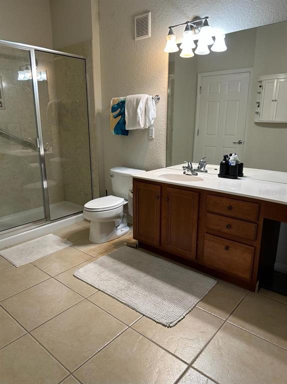 A bathroom features a glass-enclosed shower, a toilet, and a wooden vanity with a mirror — 3344 ROBERT TREND JONES DRIVE, ORLANDO, FL