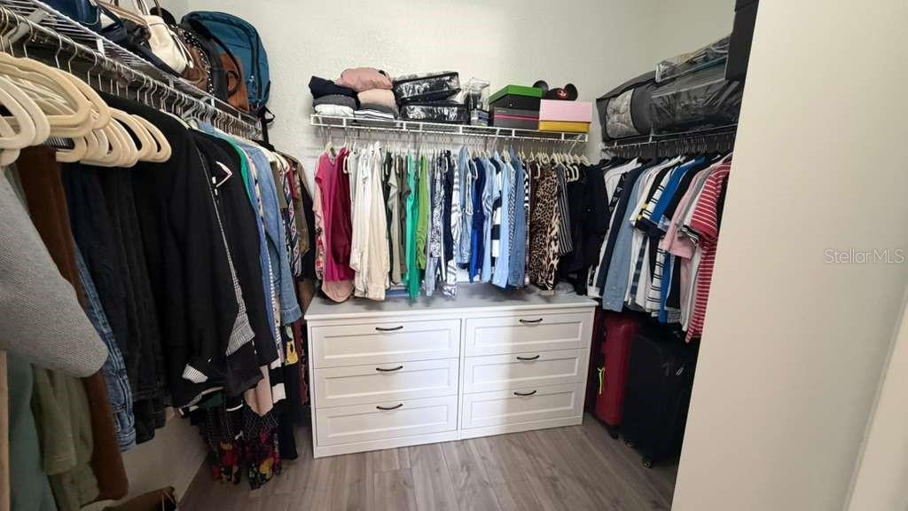 A walk-in closet features hanging clothes, a white six-drawer dresser, and upper storage shelving — 3344 ROBERT TREND JONES DRIVE, ORLANDO, FL