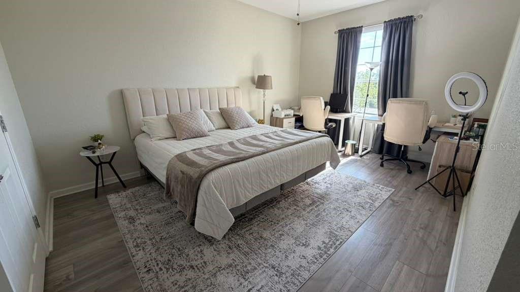 A bedroom features a bed with a tufted headboard, a rug, and two desk workstations — 3344 ROBERT TREND JONES DRIVE, ORLANDO, FL