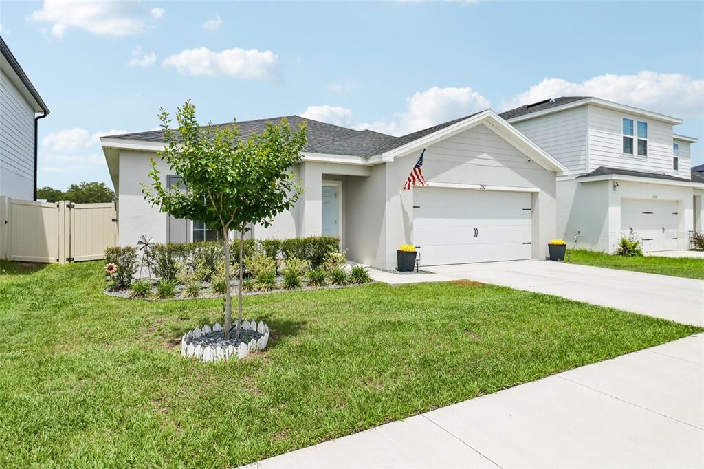 A single-story house with a white garage, a small front tree, and a grassy lawn — 2192 OKLAHOMA DRIVE, SUMTERVILLE, FL