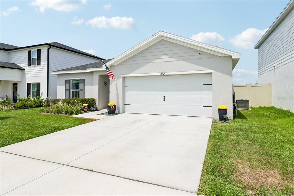 A single-story house with a white garage door, light-colored siding, and a concrete driveway — 2192 OKLAHOMA DRIVE, SUMTERVILLE, FL