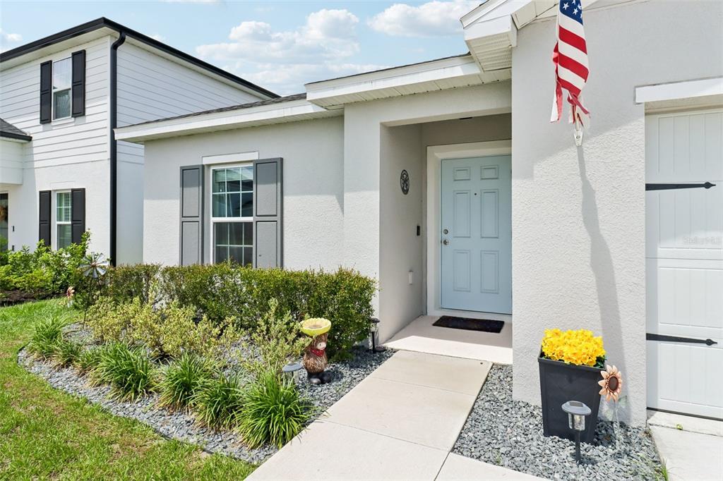 The exterior of a light-colored house features a light blue front door and a walkway — 2192 OKLAHOMA DRIVE, SUMTERVILLE, FL