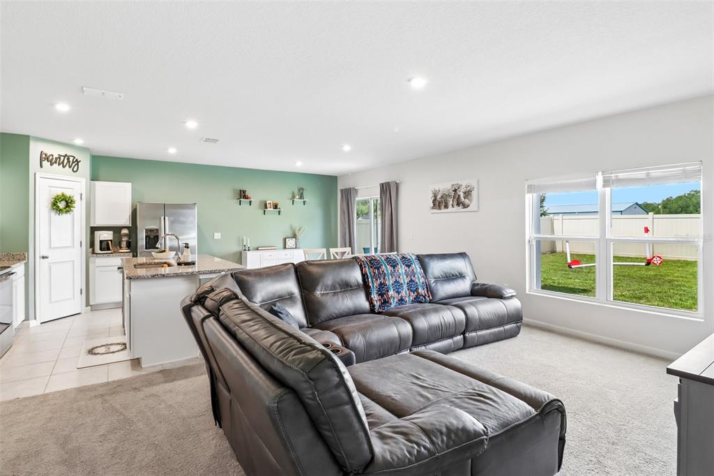 A living room with a gray sectional sofa opens to a kitchen with green walls — 2192 OKLAHOMA DRIVE, SUMTERVILLE, FL