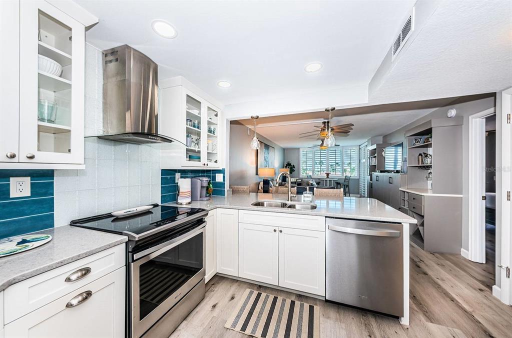 A modern kitchen with white cabinets, stainless steel appliances, and a view into the living area — 6295 BAHIA DEL MAR CIRCLE UNIT 505, ST PETERSBURG, FL