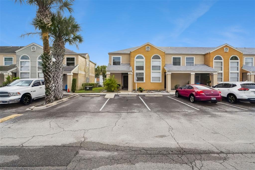 A row of two-story townhomes features yellow and tan siding with a shared parking lot — 2448 SUMMERFIELD WAY, KISSIMMEE, FL