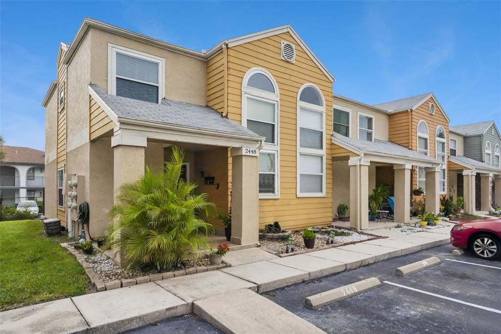 A two-story townhouse exterior with tan stucco, yellow siding, and a covered front porch — 2448 SUMMERFIELD WAY, KISSIMMEE, FL