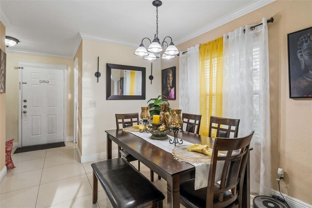 A dining room features a dark wood table with a bench, chairs, and Buddha-themed decor — 2448 SUMMERFIELD WAY, KISSIMMEE, FL