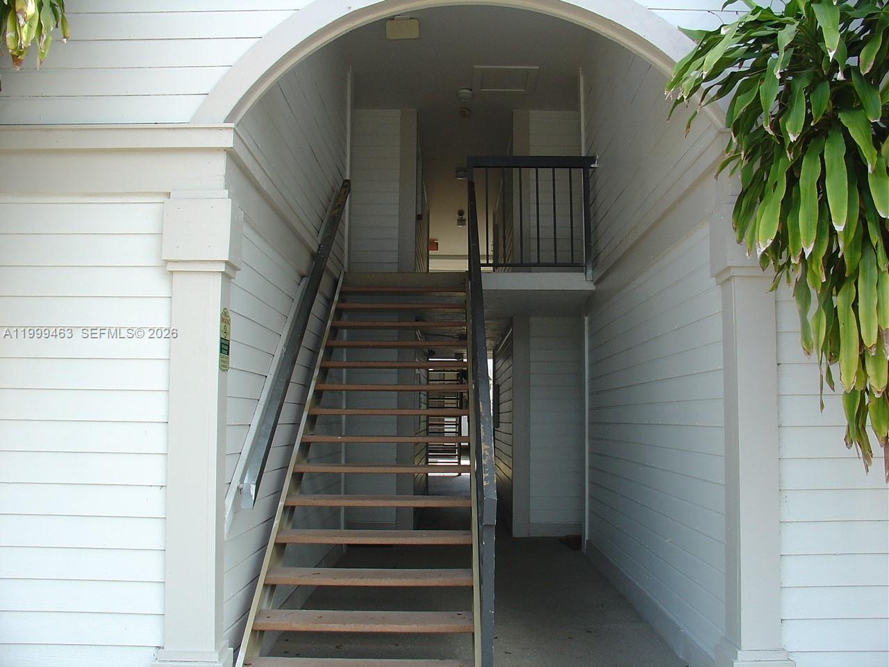 An exterior view of a staircase leading to an upper level under an arched entryway — 19025 NW 62nd Ave # 202, Hialeah FL 33015, HIALEAH, FL