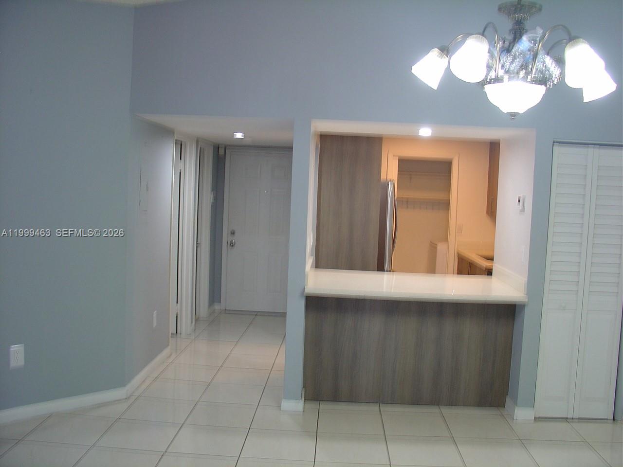 A view of a kitchen pass-through window with a breakfast bar and tiled flooring — 19025 NW 62nd Ave # 202, Hialeah FL 33015, HIALEAH, FL