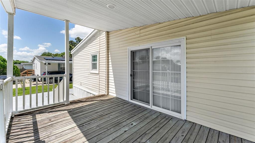 A wooden deck with a white railing sits outside a house with beige siding — 525 PERCH PLACE, LAKELAND, FL