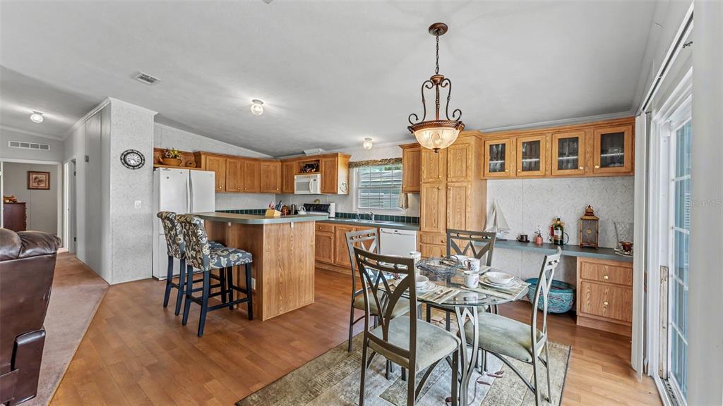 A kitchen and dining area with wood cabinets, a breakfast bar, and a glass-top table — 525 PERCH PLACE, LAKELAND, FL