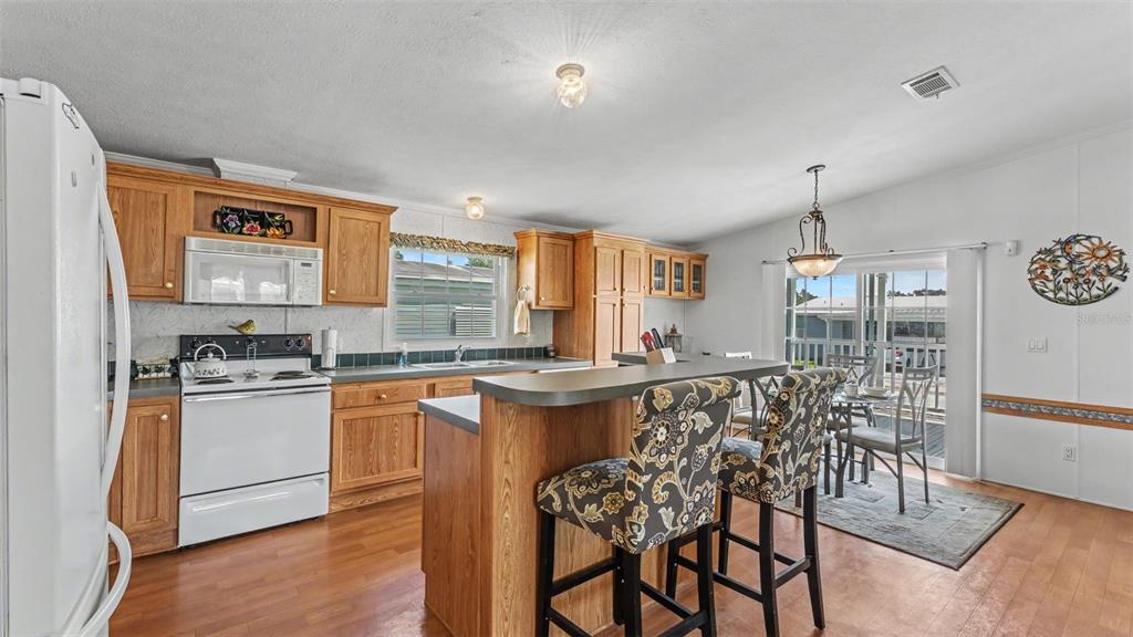 A kitchen with wood cabinets, a breakfast bar, and a dining area with sliding doors — 525 PERCH PLACE, LAKELAND, FL